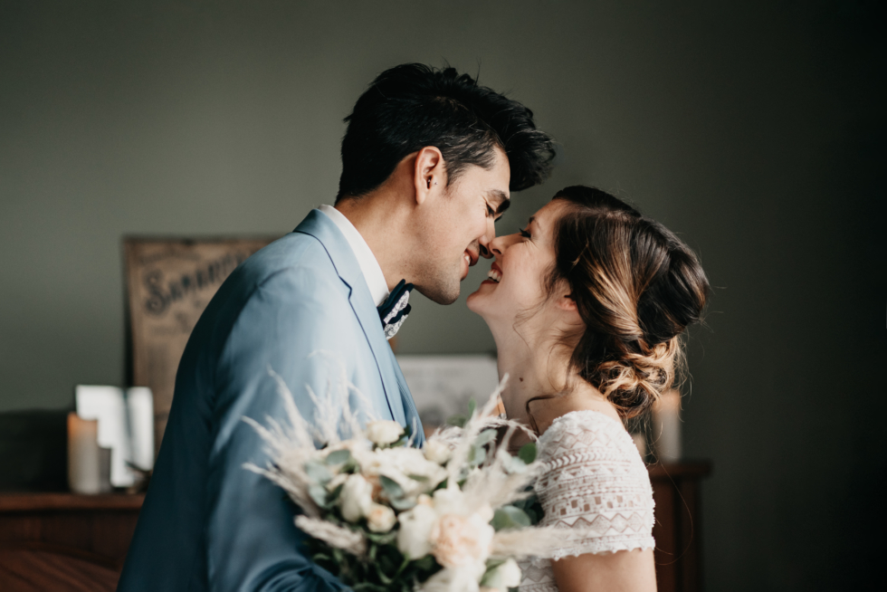 Fleuriste une couple de marié qui s'embrasse avec le bouquet en premier plan
