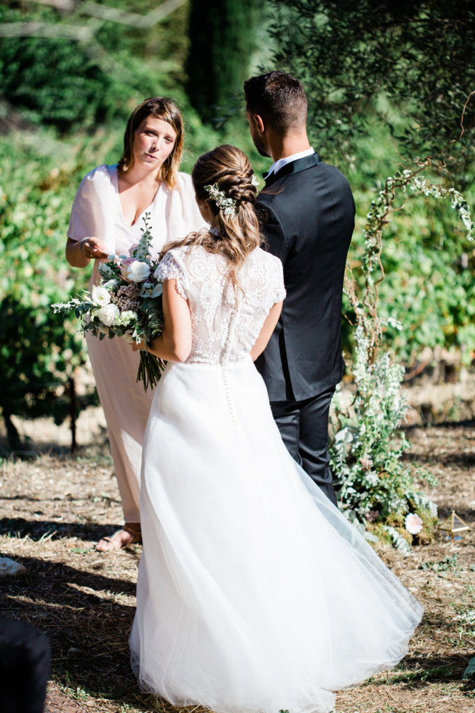 Le mariage ma passion officiante de cérémonie laïque en robe rose poudrée qui marie des mariés devant elle dans un champ de vigne