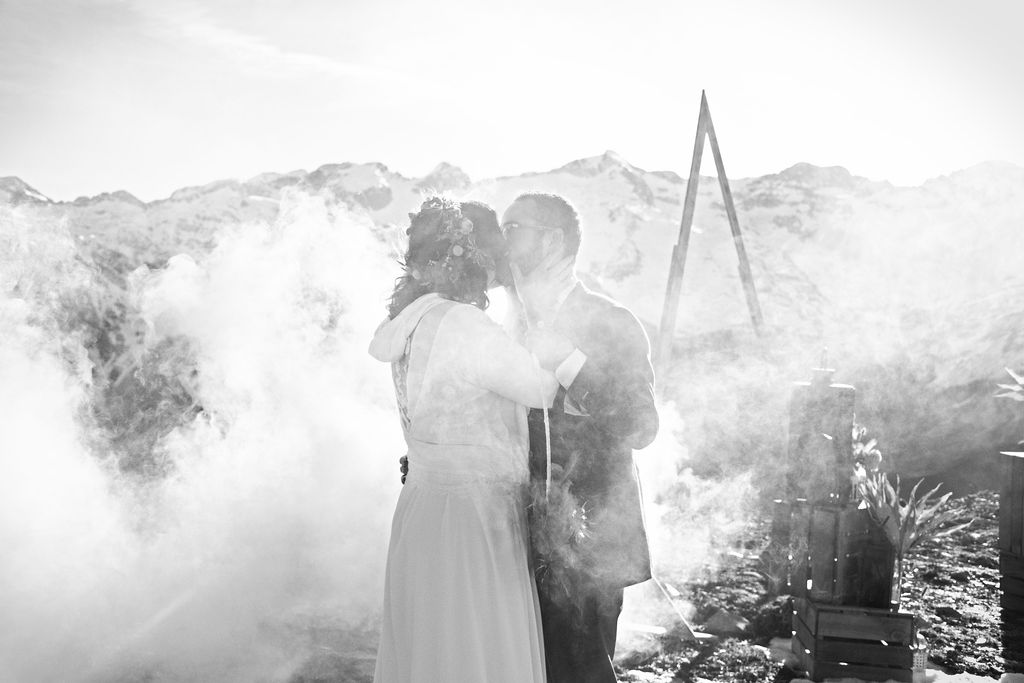Musique de mariage un couple qui s'embrasse à la fin de la cérémonie laïque devant la montagne à travers la fumée