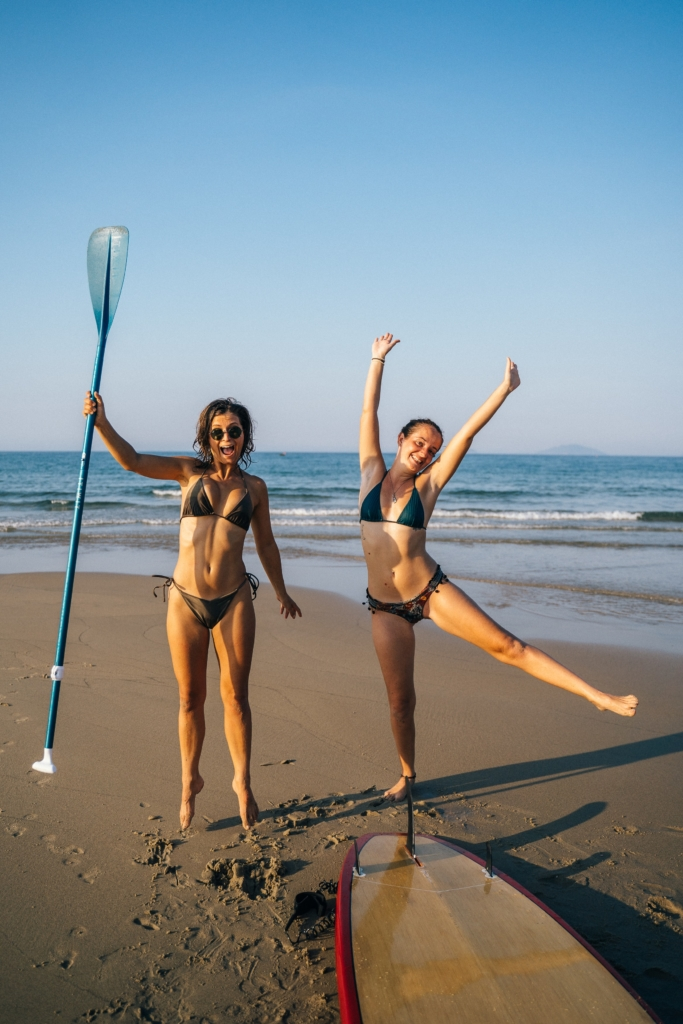 Qui inviter à mon evjf : Deux filles en maillot de bain devant le paddle avec la mer en fond