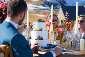 Mariage à la montagne repas avec la table dressée. Chandelles, fleurs colorée et le gâteau trône en fond