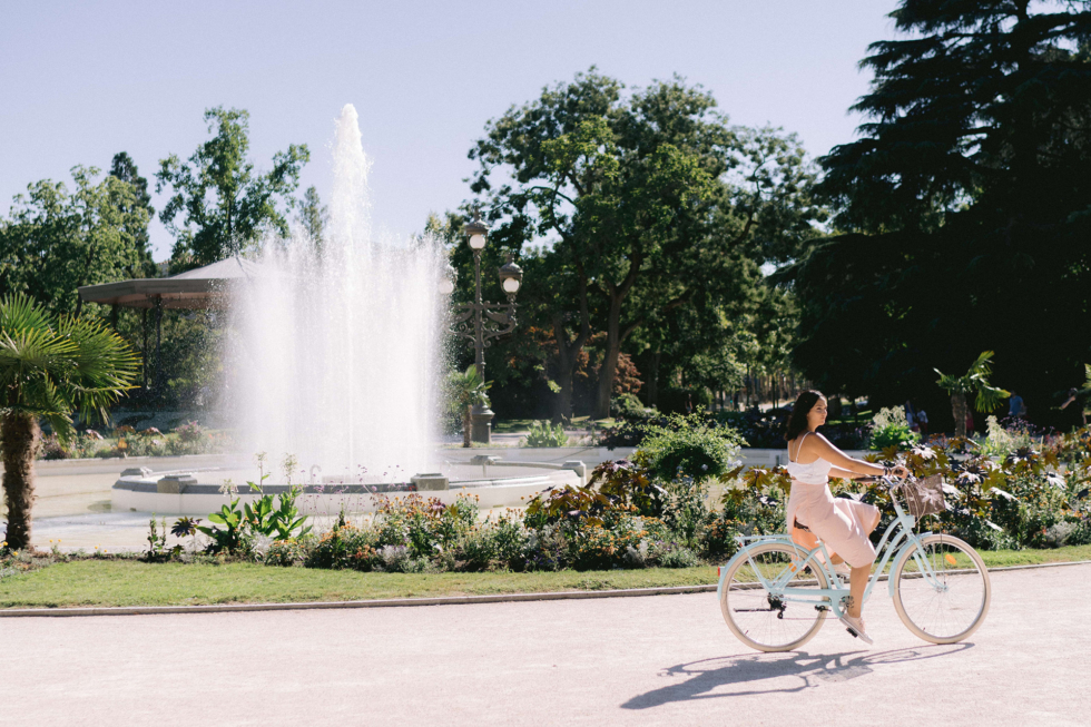 L'organisation totale de son mariage une future mariée en séance d'engagement sur sa bicyclette au jardin des plantes jupe rose poudrée débardeur blanc.