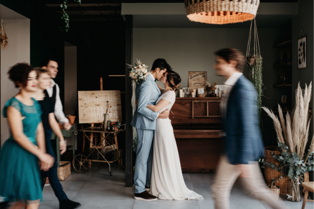 Comment choisir son costume mariage : fin de cérémonie laïque. Les mariés au centre s'embrassent et les invités passent davant